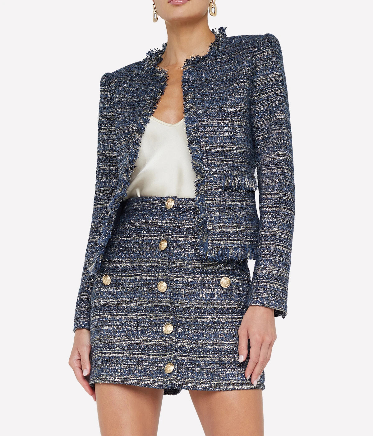 ALT text: Blue-green multi tweed jacket with raw fringe hem, styled with sleek jeans and heels.