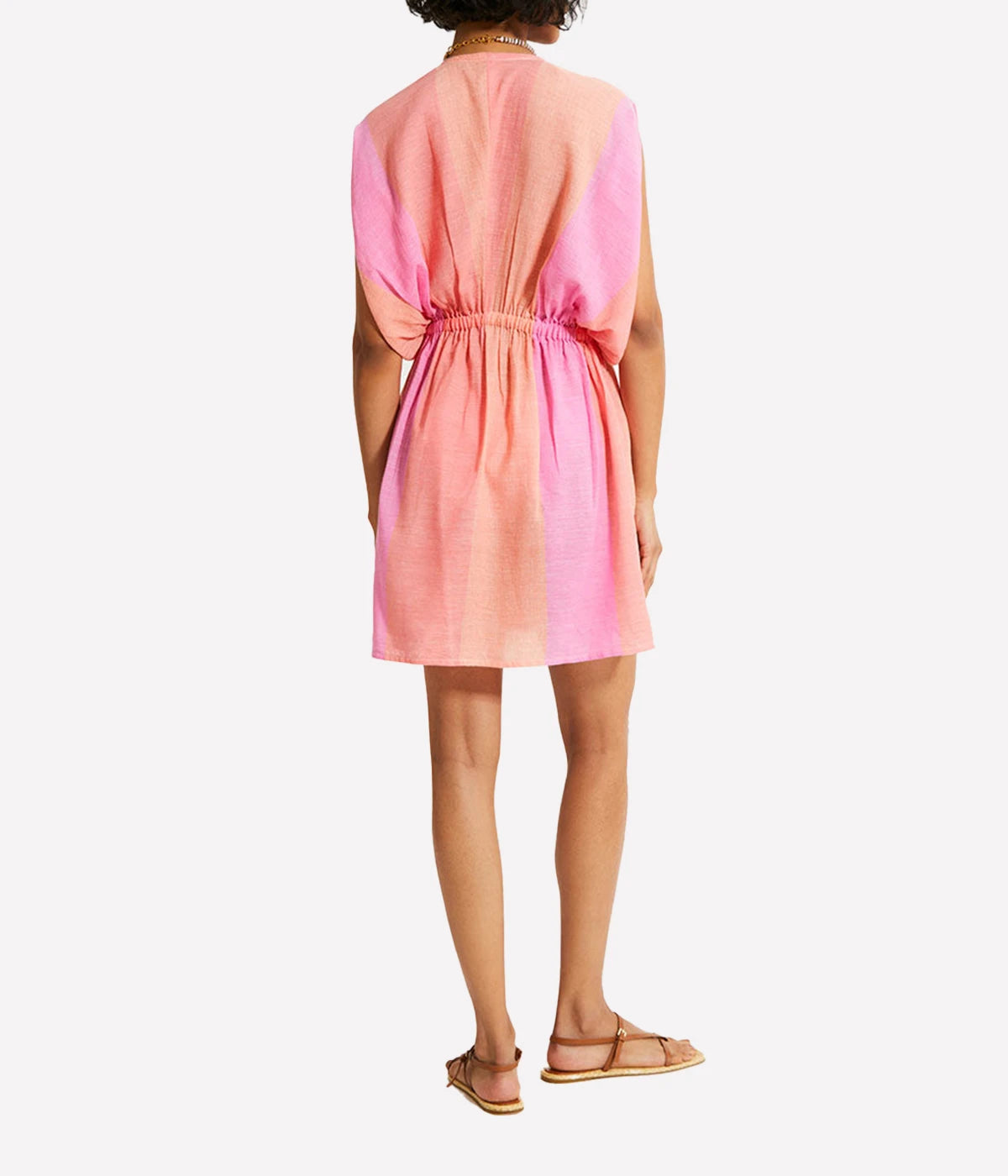 A gauzy short dress with dolman sleeves and an ombre colour block in pink, blush, and peach, styled with sandals for a relaxed resort-ready look.