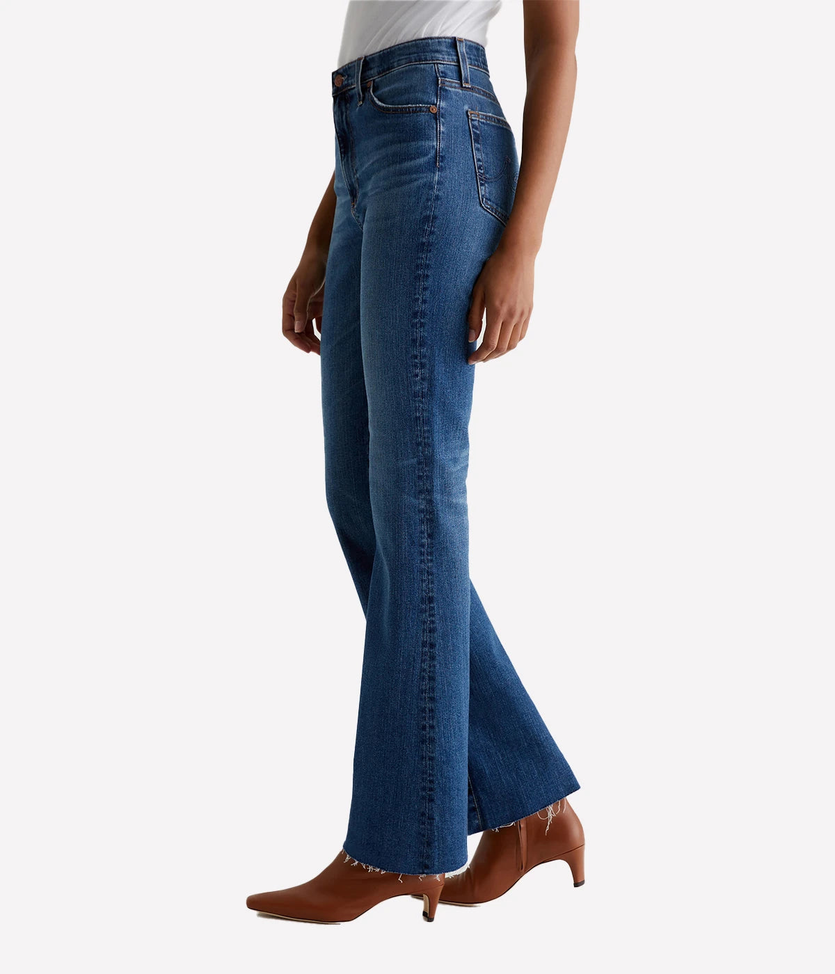 A pair of Madi high-rise flare jeans from AG in dark indigo wash with fading, whiskering, and raw hems. The jeans feature a high-rise waist and flare from the knee down, with a flattering fit through the hips.